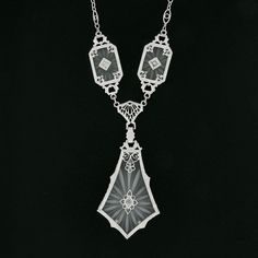 "This is a magnificent antique pendant necklace that was crafted during the art deco period in solid 14k white gold. It features three camphor glass panels with the largest dangling at the center, and each is set with a fine old single cut diamond that adds a lovely touch of sparkle to this piece. The camphor glass displays magnificent etching designs and is elegantly bezel set and framed with etched patterns throughout and further adorned with lovely floral filigree work. The largest camphor gl Luxury Art Deco Necklace With Polished Finish, Victorian White Gold Pendant Necklace, Formal Art Nouveau Diamond Jewelry, Antique White Gold Diamond Pendant Necklace, Classic Silver Diamond Necklace With Intricate Design, White Gold Diamond Necklace With Filigree For Anniversary, Anniversary Diamond Pendant Necklace With Filigree, Anniversary White Gold Diamond Necklace With Filigree, Art Deco White Gold Diamond Necklace For Formal Occasions