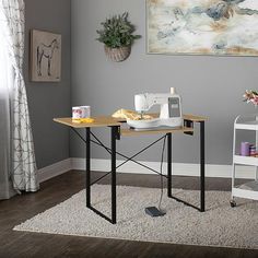 a sewing table in a living room with grey walls and white rugs on the floor