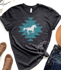 A Native American inspired TShirt featuring a horse. The perfect shirt for a vacation to Yellowstone. Bellas Canvas 3001T: T-Shirt Sizing Please reference the size chart before selecting shirt size. Use one of your own t-shirts to measure the size and fit. Then compare with the size chart provided to ensure an accurate fit. T-Shirt Materials 100% combed and ring-spun cotton. Heather colors are 90% combed and ring-spun cotton, 10% polyester. Pre-shrunk fabric. Shoulder-to-shoulder taping. Side-se Short Sleeve Cotton Top With Horse Design, Cotton Short Sleeve Top With Horse Design, Casual Short Sleeve T-shirt With Horse Design, Casual Cotton T-shirt With Horse Design, Casual Short Sleeve Tops With Horse Design, Casual Short-sleeved T-shirt With Horse Design, Yellowstone Montana, Native American Shirts, Aztec Shirt