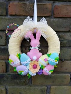 a wreath with an easter bunny on it hanging from a brick wall in front of a brick wall