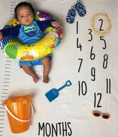 a baby laying on top of a white blanket next to a measuring line with numbers