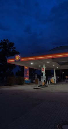 an empty gas station at night with the lights on