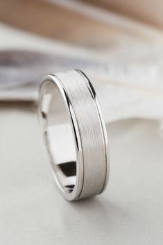 a white gold wedding ring on top of a table