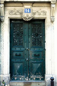 the front door to an old building with two large green doors