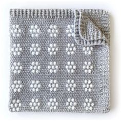 a gray and white crocheted blanket on top of a table