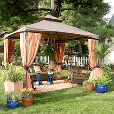 a gazebo in the middle of a yard with potted plants