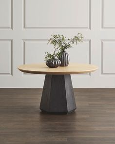 a table with two vases sitting on it's side, in front of a white wall