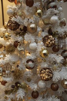 a white christmas tree with gold and silver ornaments