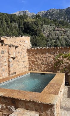 an outdoor hot tub surrounded by stone walls