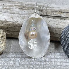 This beautiful pendant is made from a natural white oyster found on the beaches in the Cape May area. A spectacular metallic fresh water pearl is nestled inside the oyster shell showing off the treasure inside. The shell was then wire wrapped with sterling silver wire. The pendant measures 2 inches in length from the top of the bail and 1 inches wide. The pendant is on a 16" sterling silver box chain but other lengths are available in the below options. Silver Mother Of Pearl Shell Gift, Silver Shell With Pearl Pendant, Silver Shell Jewelry With Pearl Charm, Silver Pearl Shell Necklace Gift, Silver Pearl Shell Necklace As A Gift, Silver Pearl Shell Necklace For Gift, Silver Shell Necklace With Pearl Pendant, Silver Pearl Shell Necklace, Handmade Silver Abalone Shell