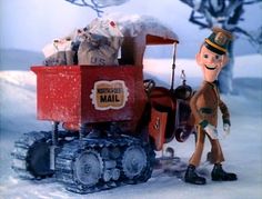 a toy man standing next to a red cart filled with bags and stuff in the snow