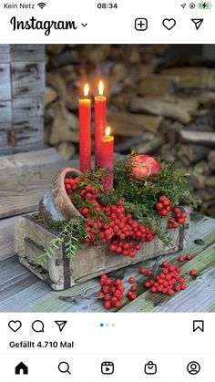 some red berries and candles are in a wooden box