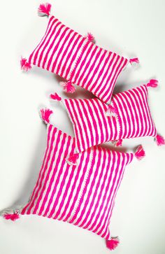 three red and white striped pillows with pink tassels