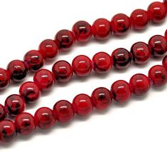 red glass beads are lined up on a white surface