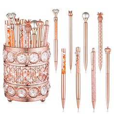 an assortment of different types of pens and pencils in pink gold - tone metal containers