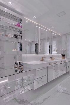 a large bathroom with white marble counter tops and mirrors on the wall, along with two sinks