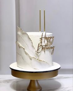 a white and gold birthday cake sitting on top of a table