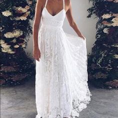 a woman wearing a white dress standing in front of flowers