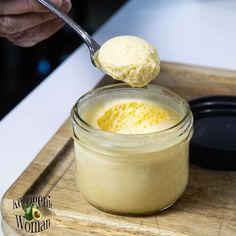 a person spooning some ice cream out of a small jar on a cutting board