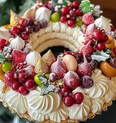 a cake decorated with fruit and decorations on top of a table in front of a christmas tree