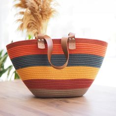 a multicolored bag sitting on top of a wooden table next to a potted plant