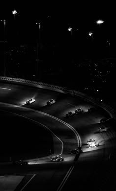 black and white photograph of cars driving down a highway in the dark at night time