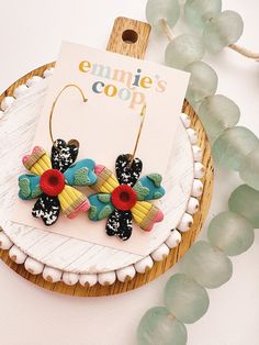 the earrings are decorated with colorful flowers on them and have gold earwires attached to them