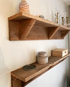 two wooden shelves on the wall with candles and other items sitting on top of them