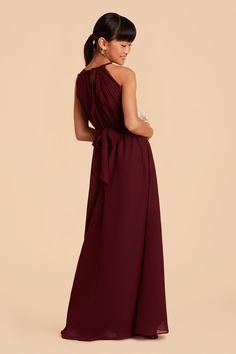 a woman in a long burgundy dress with one shoulder tied at the waist and an open back