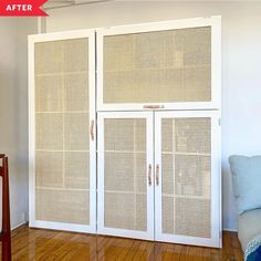 a room with a couch, chair and two white cupboards on top of wooden floors