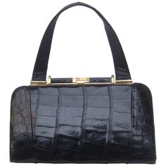 Sleek ebony vintage alligator leather handbag ca 1960s The stylish retro handbag is covered with glossy black alligator skin The handbag is designed with a sleek gilt metal clasp frame and hardware The interior is lined in ivory color vinyl designed with a zipper compartment and small pouch pocket compartment The vintage handbag is chic and timeless Measurements The handbag measures 12" inches in length across the top The length across the base of the handbag measures measures 12" 1/4 inches The handbag height from the clasp opening to the base = 7" inches The height from top of the handle to the base of the handbag measures 13" 3/4 inches The depth at the base widest section measures 2" 1/2 inches Cage Bag, Alligator Handbags, Crocodile Handbags, Retro Handbags, Patent Leather Handbags, Suede Handbags, Vintage Handbag, Vintage Purses, Vintage Purse