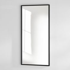 a bathroom mirror sitting on top of a white wall