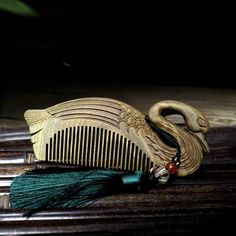 a wooden comb with a green tassel on it sitting on top of a table