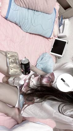 a woman laying on top of a bed next to a laptop computer and cell phone