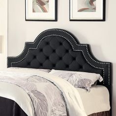 a black headboard on a bed in a room with two framed pictures above it