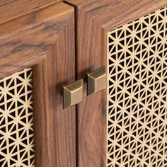 a wooden cabinet with two brass handles on it's sides and an intricate lattice design