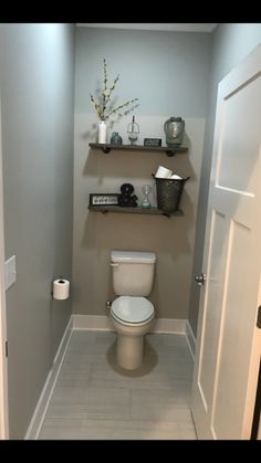 a white toilet sitting inside of a bathroom next to a shelf filled with towels and other items