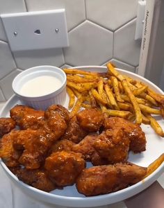 chicken wings and french fries on a white plate