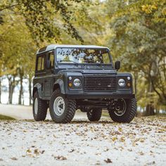 a black land rover parked on the side of a road with trees in the background