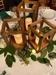 some candles are sitting in wooden boxes on a table