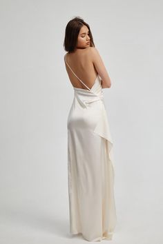 the back of a woman wearing a white dress with an asymmetrical design