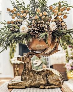 a vase filled with flowers sitting on top of a table next to a deer figurine