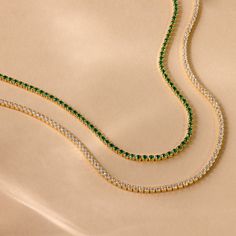 Luck is certain to find you while wearing our Emerald Tennis Choker Necklace. The vivid and brilliant color of the Emerald gemstone is perfect for a statement piece worn alone or to pair with other layering necklaces for a more boho, casual look. No matter which option you choose, you are sure to stand out. Finish/Material: 18K Gold Over Brass ∙ Rhodium Over Brass Featuring ~2mm CZ Emerald Gemstones on an adjustable 14 inch to 16 inch Choker Necklace Part of our Diamond and Pavé Collection Model Gold Tennis Necklace With Gemstones As Gift, Everyday Fine Jewelry Green Necklaces, Green Fine Jewelry Necklace For Everyday, Everyday Fine Jewelry Green Necklace, Green Jewelry With Delicate Chain For Layering, Gold Emerald Necklace For Everyday Wear, Tennis Choker Necklace, Initial Tag Necklace, Dainty Initial Necklace