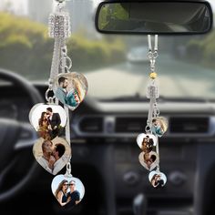 two hearts hanging from the dashboard of a car, with photos attached to them and dangling from chains