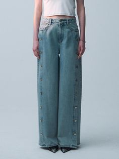 These Kentone wide denim pants showcase a bold and distinctive design, featuring a full-length row of buttons down each side that not only add a unique visual element but also allow for custom styling options. The wide-leg silhouette emphasizes a modern take on classic denim, making these pants a standout piece. The high waist and structured denim fabric enhance the overall fit, providing both style and comfort. - These pants are defined by their dual side button closures which offer versatility in how they can be worn and styled.- The wide-leg design creates a dramatic and fashionable statement, suitable for various occasions.- Crafted from high-quality denim, these pants ensure durability and a comfortable fit that conforms to the wearer over time.- Their high-waisted cut pairs well Modern Wide-leg Denim Blue Pants, Chic Full-length Rigid Denim Pants, Denim Blue Washed Full-length Pants, Light Blue Full-length Denim Pants, Wide-leg Rigid Denim Pants In Denim Blue, Denim Fabric, Denim Pants, Full Length, Overalls