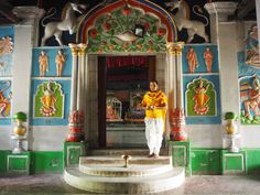 a man standing in front of a colorful building with paintings on the walls and columns