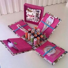 sewing supplies are displayed in pink boxes on a table