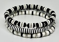 Set of 3 Black and White, hand beaded, stretch bracelets. Each strand is made with 6mm Heishi beads with silver accents. Can be customized with wording of your choice. Black And White Clay Bracelet, Heishi Bracelet Patterns, Bracelet Perle Heishi Homme, Black And White Clay Bead Bracelet, Western Clay Bead Bracelet Ideas, Heishi Bracelet Ideas, Beads Bracelet Ideas, Black And White Bracelets, Bracelets Stacking