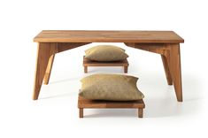 two pillows sit under a wooden table with one cushion on the bottom and another pillow on the bottom