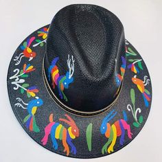 a black hat with multicolored horses on the front and sides, sitting on a white surface